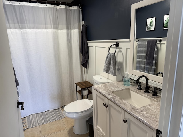 full bathroom featuring tile patterned flooring, a wainscoted wall, toilet, a shower with shower curtain, and vanity