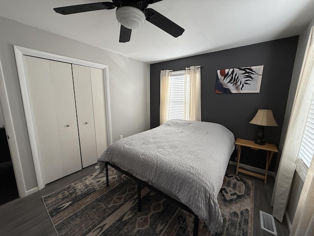 bedroom with ceiling fan, visible vents, a closet, and wood finished floors