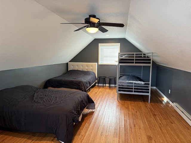 bedroom featuring wood finished floors, baseboards, a baseboard radiator, vaulted ceiling, and a textured ceiling