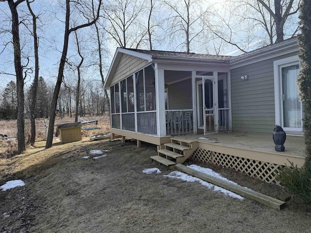 view of home's exterior with a sunroom and a wooden deck