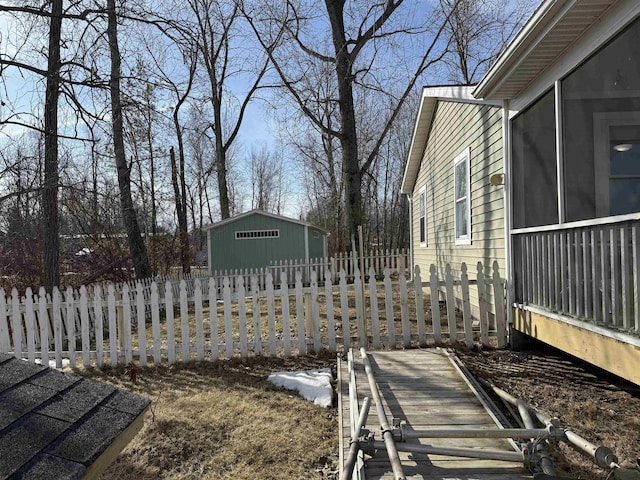 view of yard featuring a sunroom, an outdoor structure, and fence