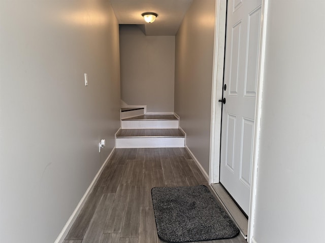 corridor featuring baseboards, wood finished floors, and stairs