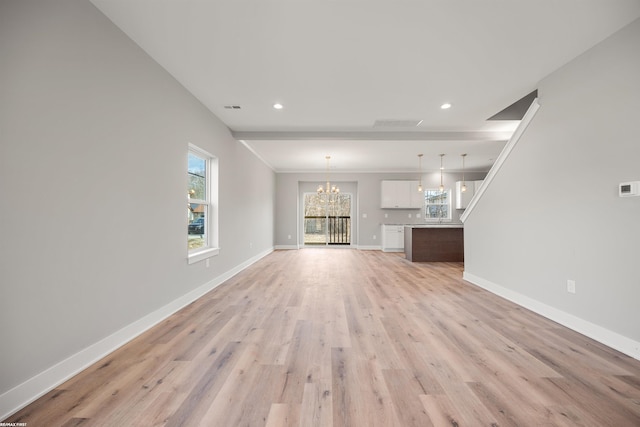 unfurnished living room with visible vents, a notable chandelier, light wood-style flooring, recessed lighting, and baseboards