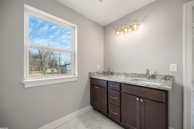 bathroom featuring double vanity, marble finish floor, baseboards, and a sink