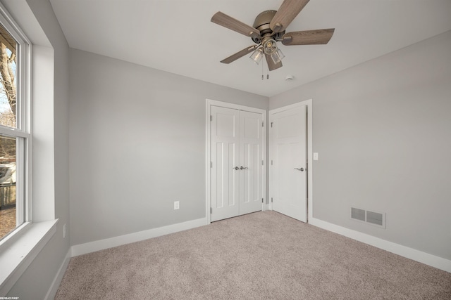 carpeted spare room featuring visible vents, baseboards, and a ceiling fan