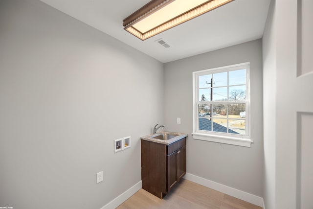 clothes washing area with visible vents, baseboards, hookup for a washing machine, cabinet space, and a sink