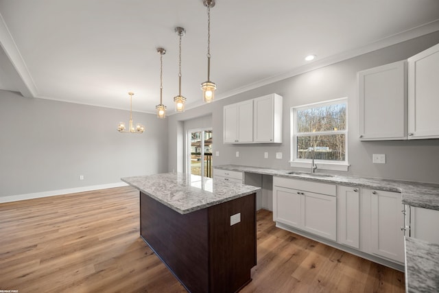 kitchen with a center island, light wood-type flooring, crown molding, and a sink