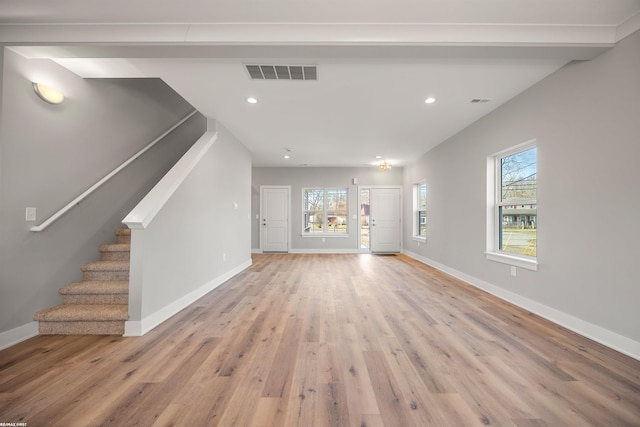 unfurnished living room featuring light wood finished floors, visible vents, stairway, and baseboards