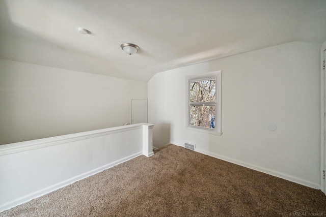 carpeted spare room featuring visible vents and lofted ceiling