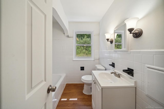 bathroom with vanity, wood finished floors, a wainscoted wall, toilet, and a washtub