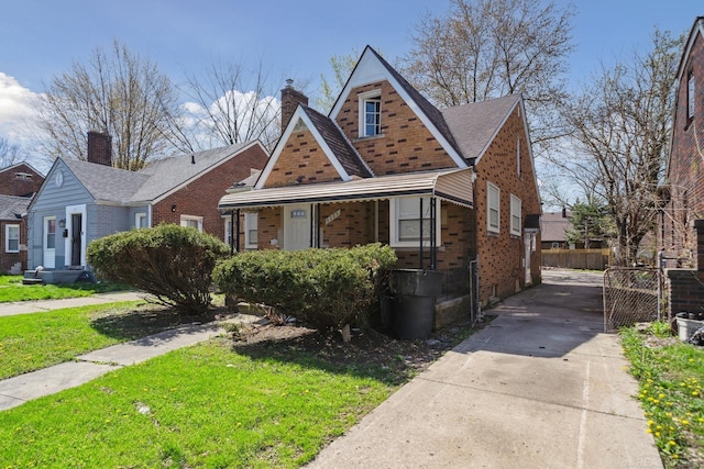 view of front of property with brick siding, a front lawn, fence, a chimney, and driveway