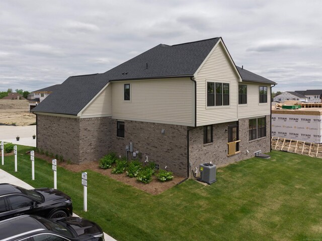 17447 Megan Dr, Macomb, MI 48042 - view of home's exterior with central air condition unit, brick siding, a lawn, and a shingled roof