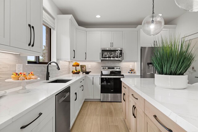 17447 Megan Dr, Macomb, MI 48042 - kitchen featuring stainless steel appliances, a sink, light wood-style flooring, light stone counters, and recessed lighting