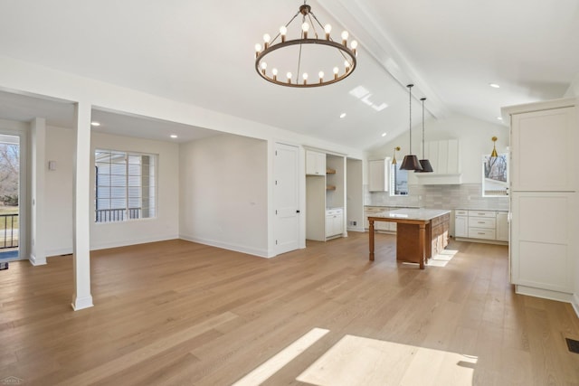 7474 Connies Dr, Shelby Twp, MI 48316 - kitchen with light wood-type flooring, vaulted ceiling with beams, white cabinetry, tasteful backsplash, and a center island