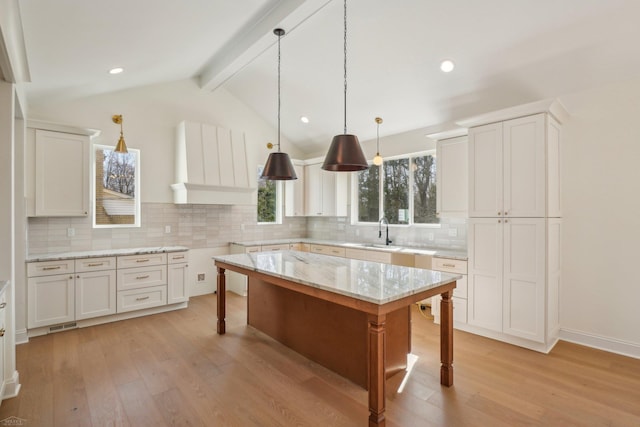 7474 Connies Dr, Shelby Twp, MI 48316 - kitchen featuring light wood-style flooring, a sink, a kitchen breakfast bar, backsplash, and hanging light fixtures