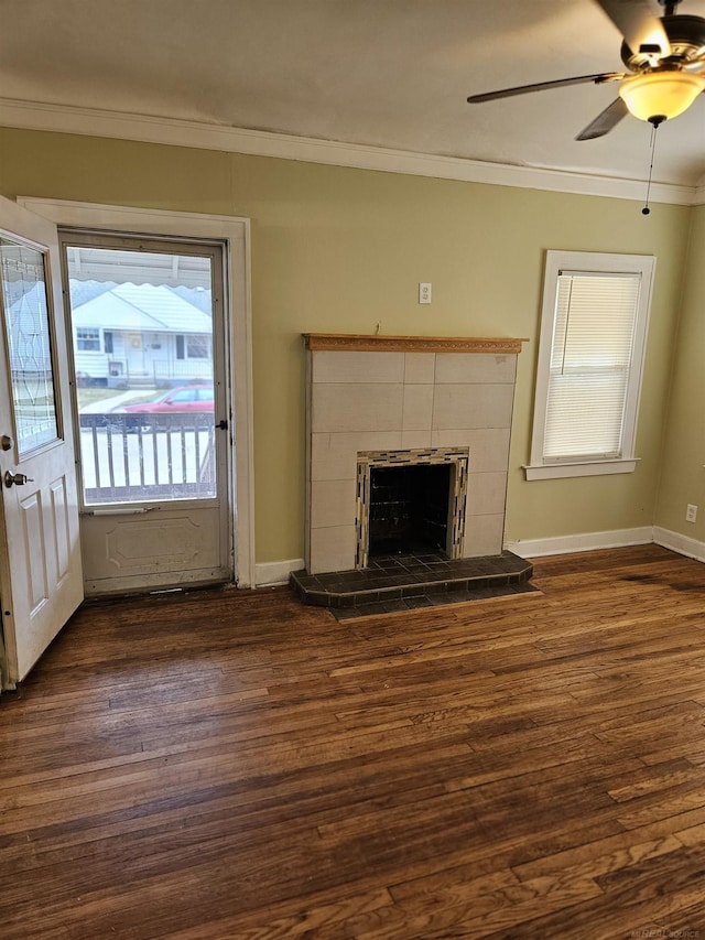 unfurnished living room with ceiling fan, dark wood-type flooring, a tile fireplace, and ornamental molding