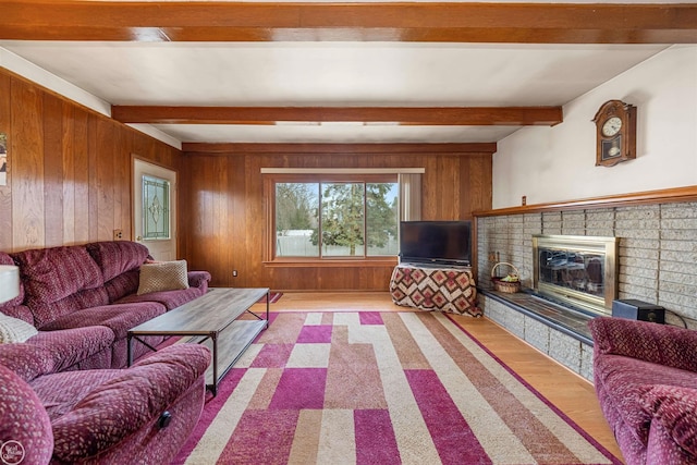 living room featuring wood walls, beamed ceiling, a fireplace, and wood finished floors