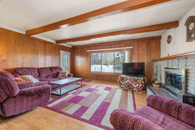 living room with a brick fireplace, beam ceiling, wooden walls, and light wood finished floors