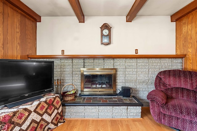 living room featuring a fireplace, wood finished floors, and beamed ceiling