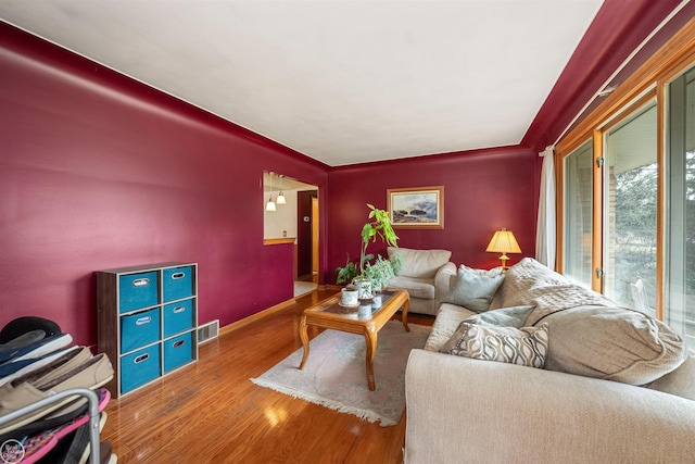 living room with baseboards, visible vents, and wood finished floors