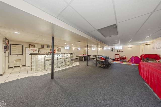 interior space with freestanding refrigerator, recessed lighting, a drop ceiling, and a community bar