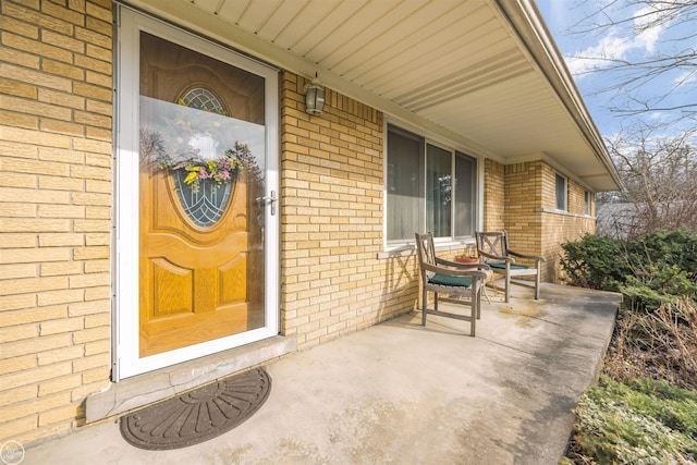 view of exterior entry featuring brick siding and a porch
