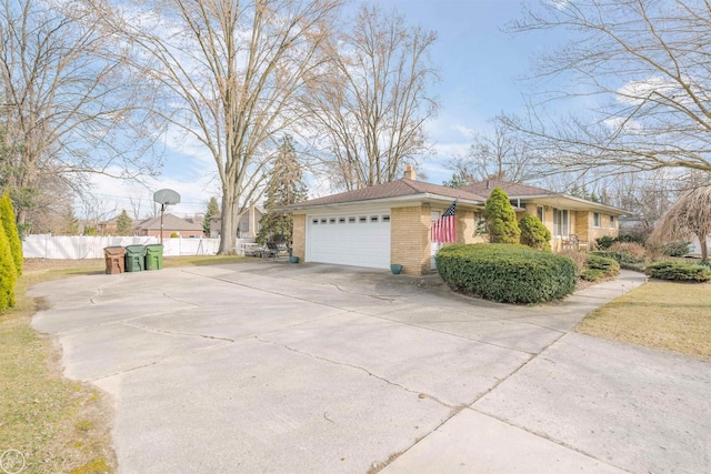 view of side of home with concrete driveway, fence, brick siding, a garage, and a chimney