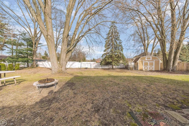 view of yard with an outdoor fire pit, a fenced backyard, an outbuilding, and a storage unit