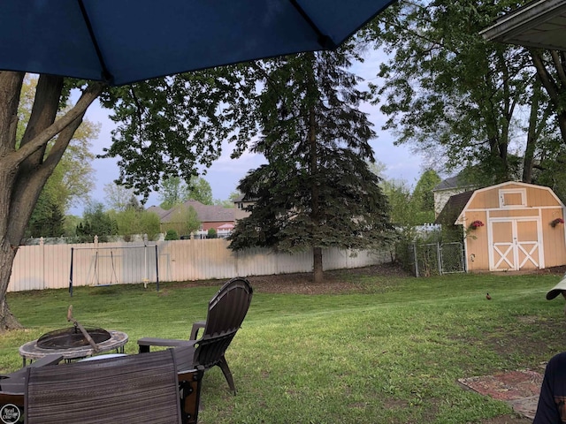 view of yard featuring a storage unit, an outdoor fire pit, an outbuilding, and fence