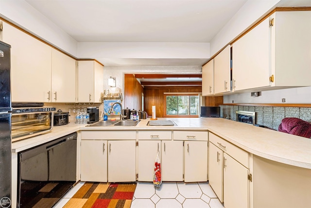 kitchen featuring black dishwasher, light countertops, a sink, and tasteful backsplash