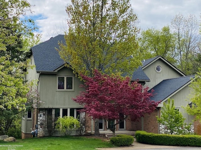 view of front of property with roof with shingles and a front yard
