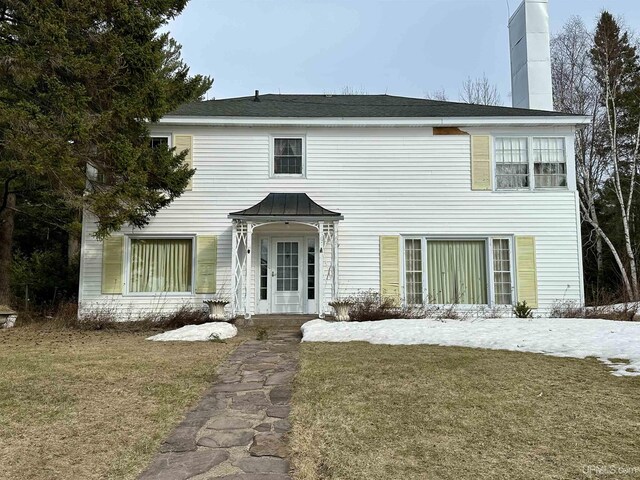 back of property with a lawn and a chimney