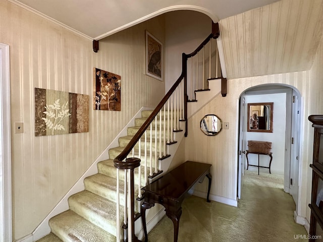staircase with carpet flooring, wallpapered walls, arched walkways, and baseboards
