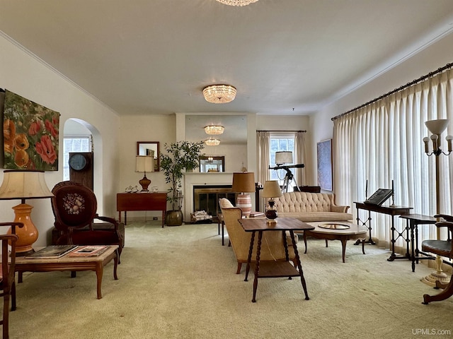 living room with arched walkways, ornamental molding, carpet, and a glass covered fireplace