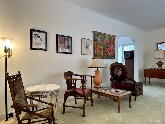 living area featuring arched walkways, baseboards, crown molding, and carpet