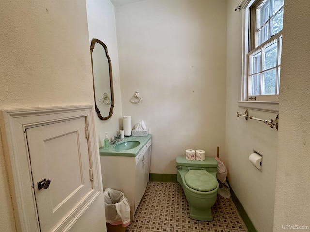 bathroom featuring toilet, vanity, and baseboards