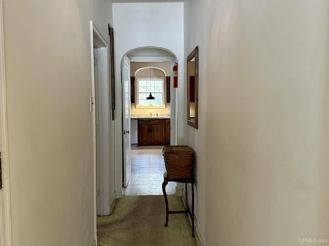 hall featuring a sink and light colored carpet