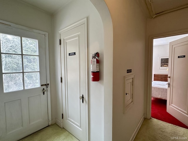 interior space featuring arched walkways, baseboards, and light colored carpet