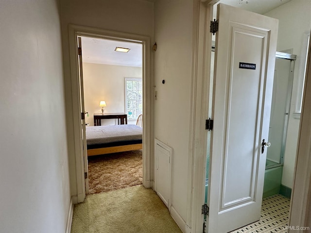 hallway with baseboards and light colored carpet