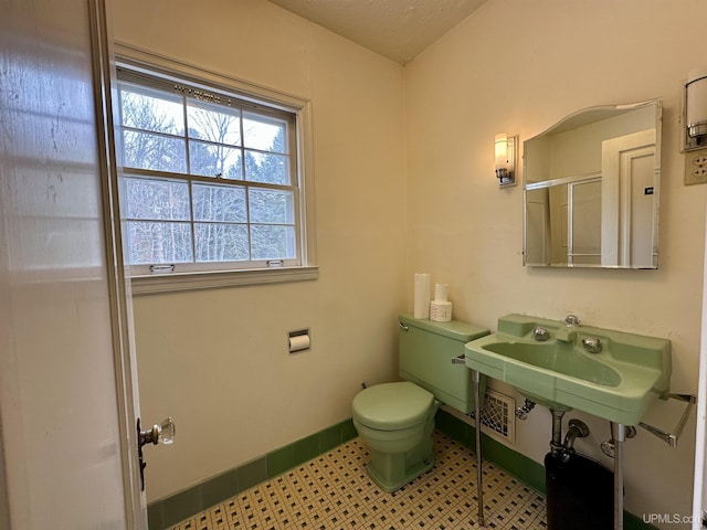 bathroom with baseboards, toilet, and an enclosed shower