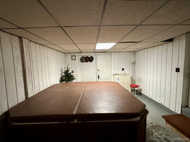 rec room featuring wooden walls, concrete floors, and a paneled ceiling
