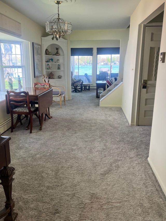 carpeted dining space with a chandelier and a baseboard radiator