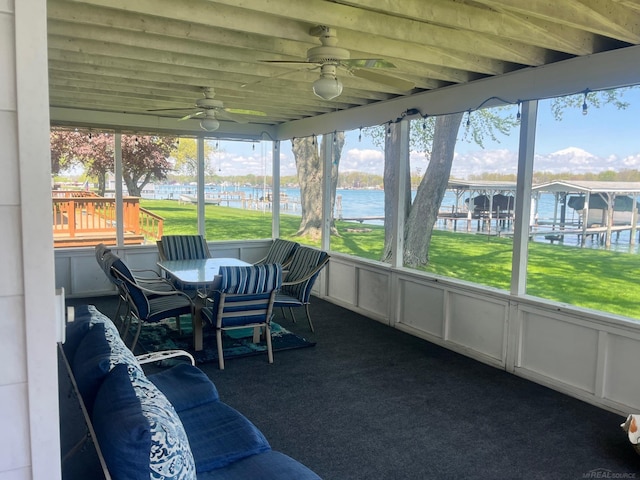 sunroom featuring ceiling fan and a water view