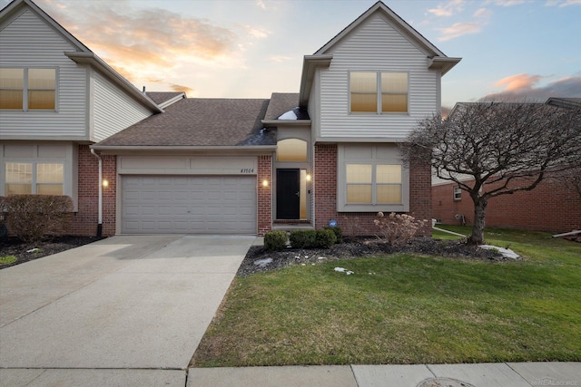 view of front of house with concrete driveway, roof with shingles, brick siding, a garage, and a yard