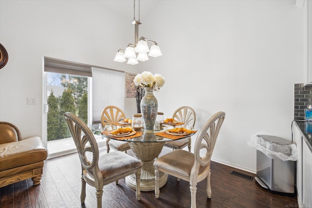 dining space with wood-type flooring, a notable chandelier, baseboards, and visible vents