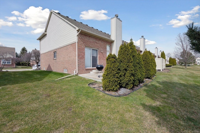 exterior space featuring a lawn, brick siding, a chimney, and a patio area