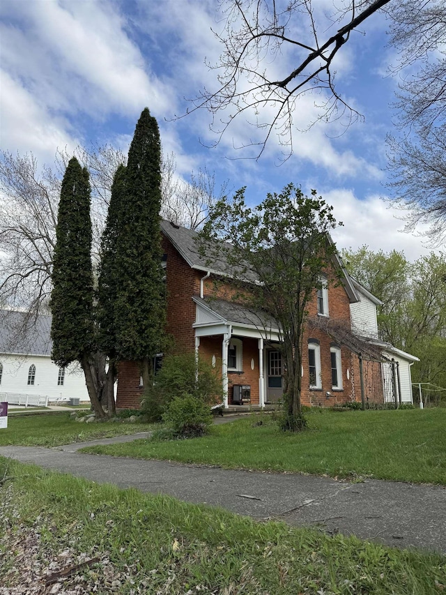view of front of property with a porch, a front lawn, and brick siding