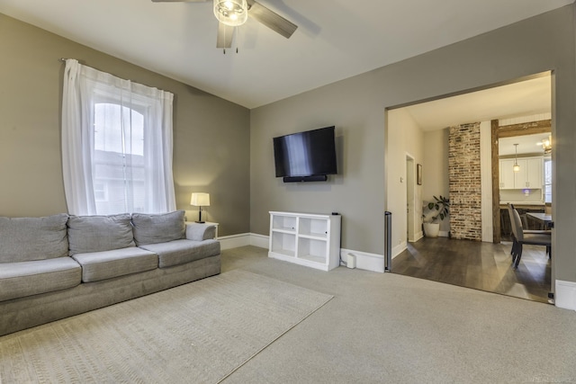 carpeted living room featuring a ceiling fan and baseboards