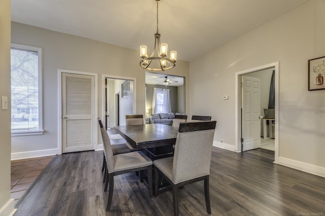 dining room with ceiling fan with notable chandelier, dark wood-style floors, and baseboards