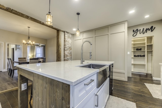 kitchen featuring hanging light fixtures, a sink, dark wood-style floors, a kitchen island with sink, and a notable chandelier